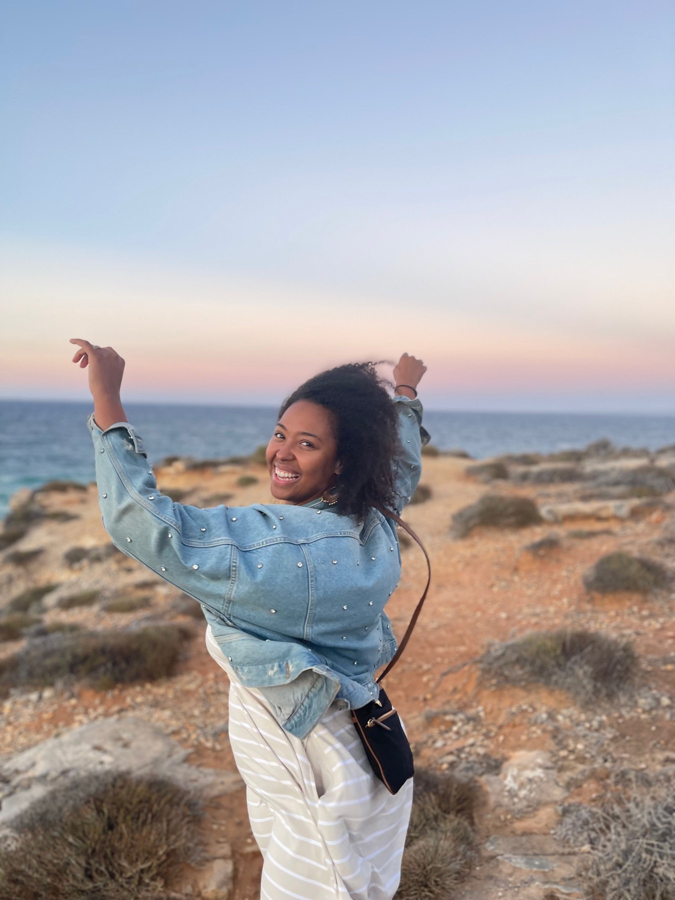Sidney on the coast at sunset, looking back and smiling