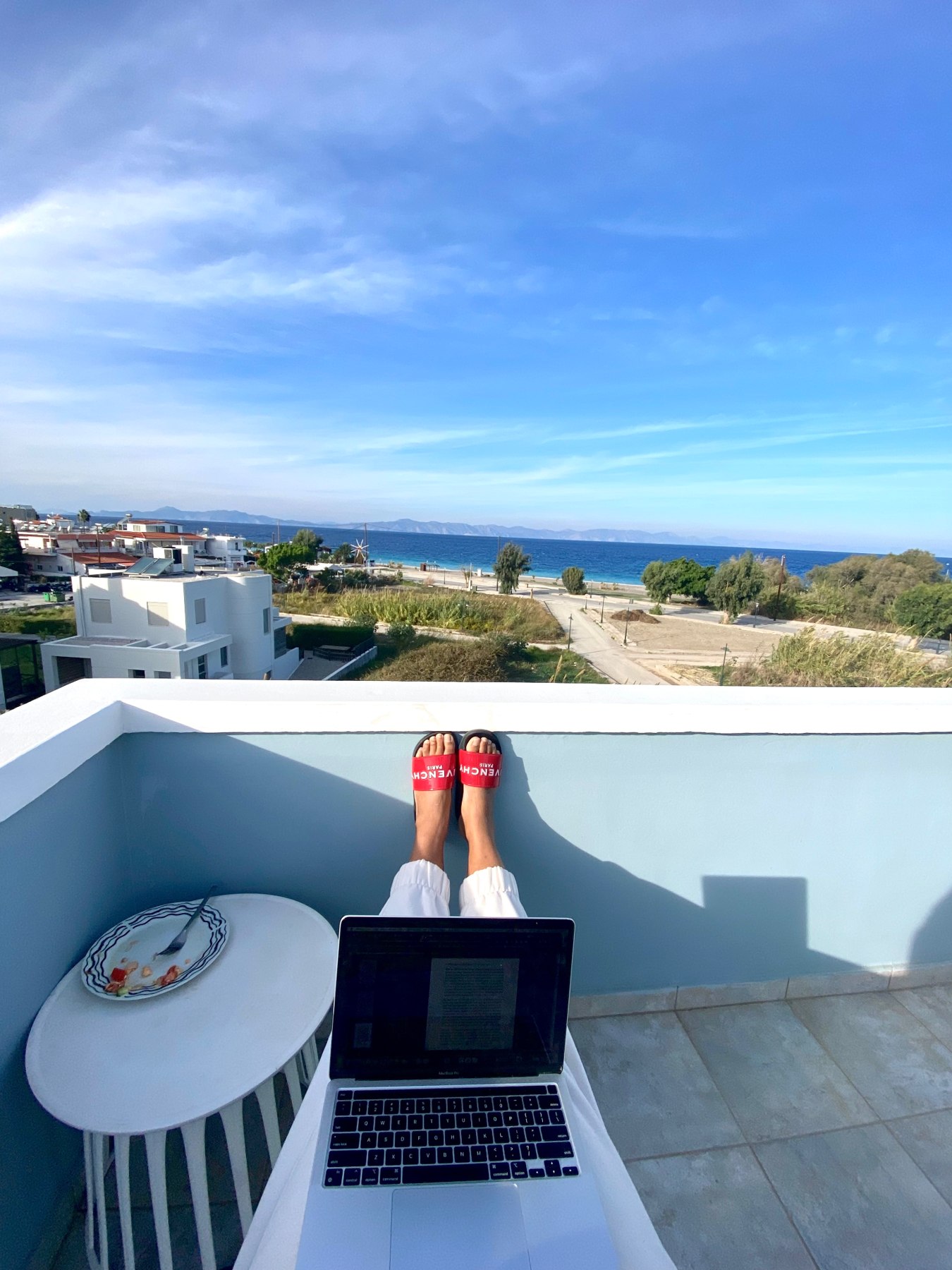 An open laptop on a terrace with a wide sea view